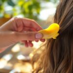 gros-plan-dune-main-clipant-une-barrette-en-forme-de-banane-dans-des-cheveux-lumiere-douce-du-matin-arriere-plan-flou-avec-plantes-en-pot-et-table-en-bois
